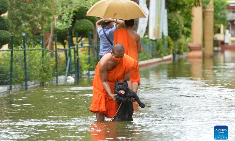 A monk saves a dog on a flooded road on the outskirts of Bangkok, Thailand, on Sept. 3, 2021.Photo:Xinhua