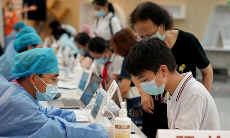 A medical worker inquires a boy about his health condition before providing him with COVID-19 vaccination at a vaccination site in Xuhui District of Shanghai, east China, Sept. 3, 2021.Photo:Xinhua