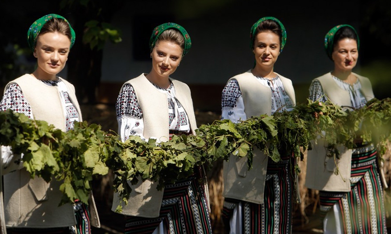 Women dressed in traditional clothes hold vine branches while performing a demonstration of ancient wine making at an autumn fair at Romanian Village Museum in Bucharest, Romania, Sept. 11, 2021.(Photo: Xinhua)