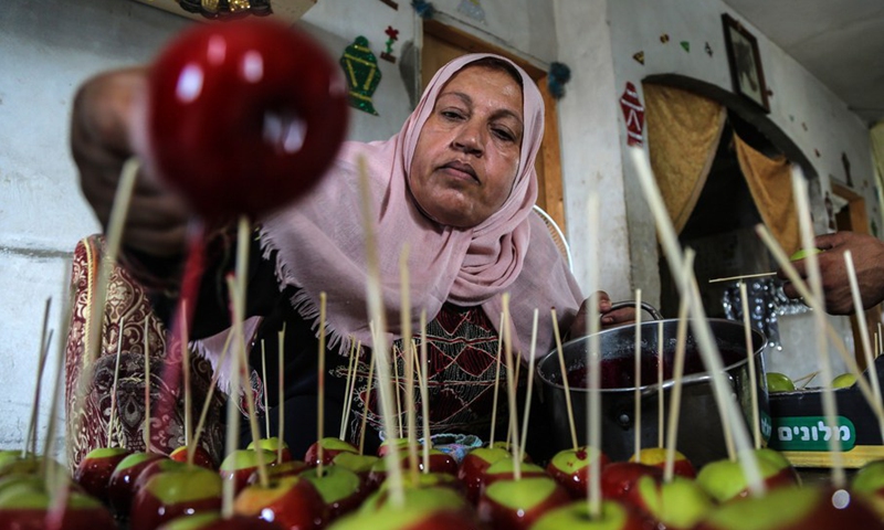 Palestinian woman Hanan Hamad makes candy apples in her house in the northern Gaza town of Beit Hanoun, on Sept. 14, 2021.(Photo: Xinhua)