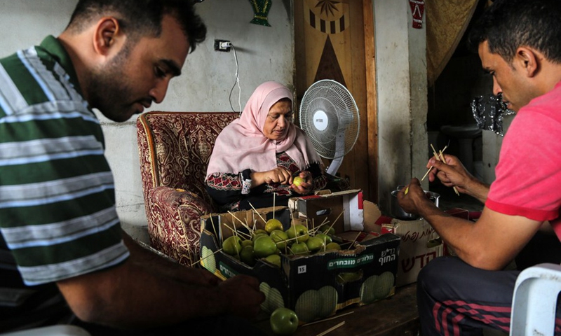 Palestinian woman Hanan Hamad and her sons make candy apples in her house in the northern Gaza town of Beit Hanoun, on Sept. 14, 2021.(Photo: Xinhua)