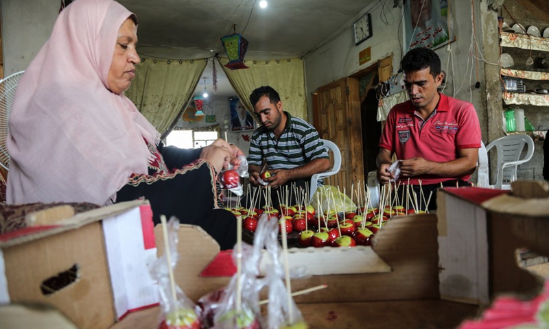 Palestinian woman Hanan Hamad and her sons make candy apples in her house in the northern Gaza town of Beit Hanoun, on Sept. 14, 2021.(Photo: Xinhua)