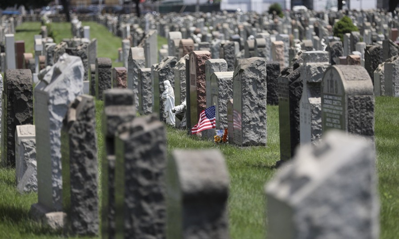 A U.S. national flag and flowers are seen at a cemetery in New York, the United States, July 29, 2020.(Photo: Xinhua)
