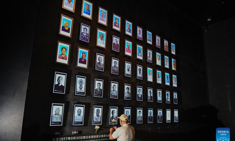 A relative of Nanjing Massacre survivor Cai Lihua presents a flower at the Memorial Hall of the Victims in Nanjing Massacre by Japanese Invaders in Nanjing, capital of east China's Jiangsu Province, Sept. 18, 2021. Cai Lihua passed away this year. The memorial hall held a ceremony on Saturday to commemorate Nanjing Massacre survivors who have passed away this year. At present, the number of registered survivors of the massacre has decreased to 64. Photo: Xinhua