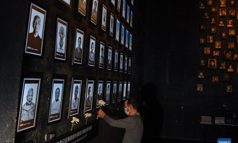 A relative of Nanjing Massacre survivor Li Rufu presents a flower at the Memorial Hall of the Victims in Nanjing Massacre by Japanese Invaders in Nanjing, capital of east China's Jiangsu Province, Sept. 18, 2021. Li Rufu passed away this year. The memorial hall held a ceremony on Saturday to commemorate Nanjing Massacre survivors who have passed away this year. At present, the number of registered survivors of the massacre has decreased to 64. Photo: Xinhua