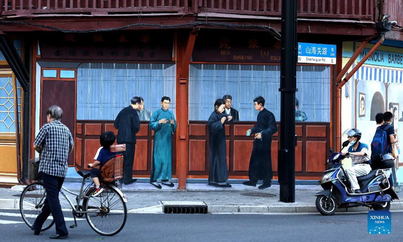 People pass by a wall painting depicting life in small alley in old residential area of Shanghai, east China, Sept. 19, 2021. Photo: Xinhua