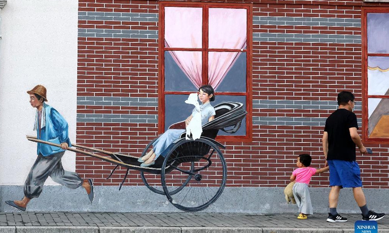 People pass by a wall painting depicting life in small alley in old residential area of Shanghai, east China, Sept. 19, 2021. Photo: Xinhua