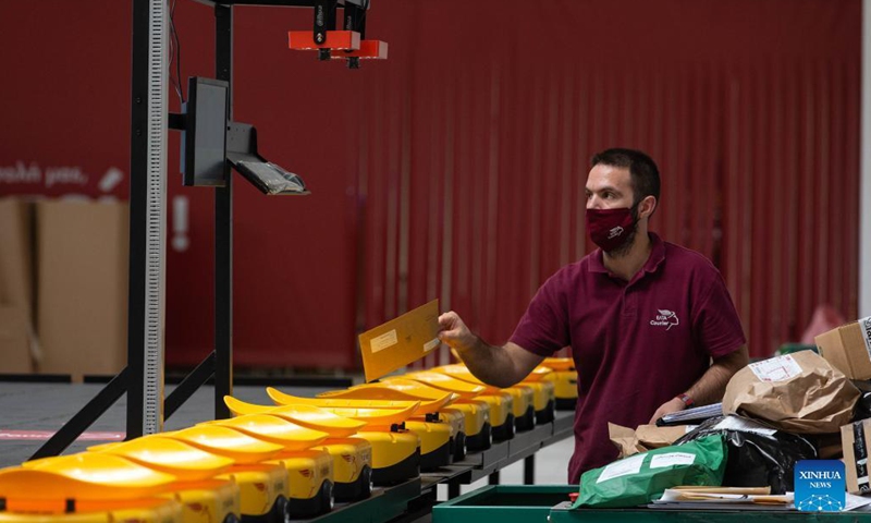An employee of Greece's national postal services provider Hellenic Post (ELTA in Greek) works with a Chinese-made robotic system for sorting mail items at the facilities of ELTA at Kryoneri, a northern suburb of Athens, Greece, Sept. 14, 2021. The ELTA in Greek has started using a Chinese-made robotic system for sorting mail items, aiming to accelerate the process and improve service for customers.(Photo: Xinhua)