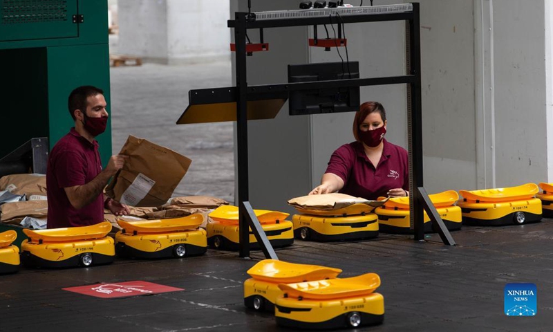 Employees of Greece's national postal services provider Hellenic Post (ELTA in Greek) work with a Chinese-made robotic system for sorting mail items at the facilities of ELTA at Kryoneri, a northern suburb of Athens, Greece, Sept. 14, 2021. The ELTA in Greek has started using a Chinese-made robotic system for sorting mail items, aiming to accelerate the process and improve service for customers.(Photo: Xinhua)