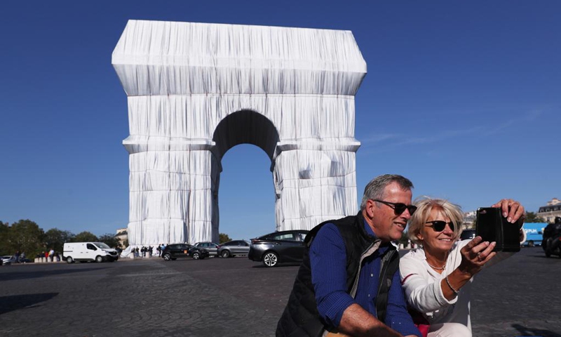 People take souvenir photos in front of the wrapped Arc de Triomphe in Paris, France, Sept. 21, 2021. The entire Arc de Triomphe at the top of the Champs-Elysees in Paris is to stay wrapped in fabric for two weeks, an art installation conceived by the late artist Christo and inaugurated on Thursday by French President Emmanuel Macron.(Photo: Xinhua)