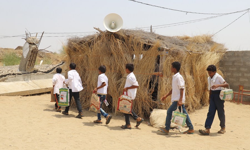 Carrying school bags made from food bags, children line up to enter their straw hut classroom at a primary school in Hajjah Province, Yemen, Sept. 20, 2021.(Photo: Xinhua)