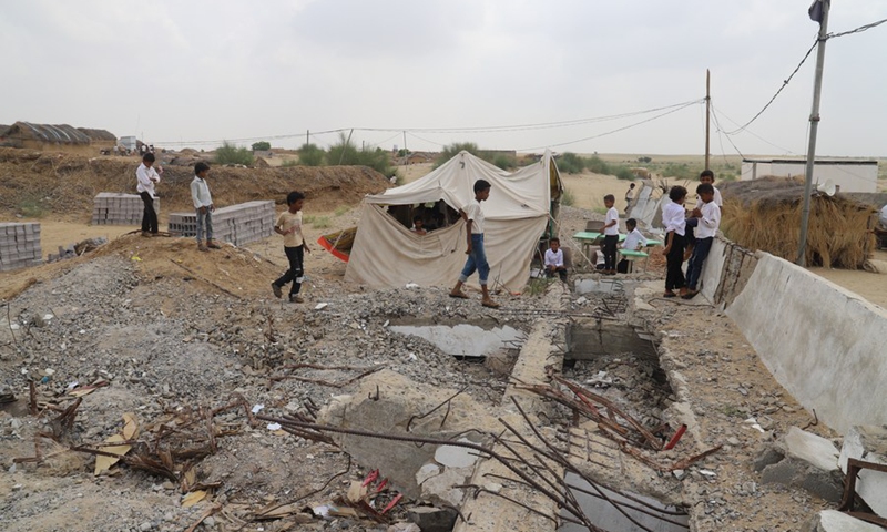 Children walk past ruins of school buildings at a primary school, which has tents, straw huts and wooden cabins as classrooms, in Hajjah Province, Yemen, Sept. 20, 2021.(Photo: Xinhua)