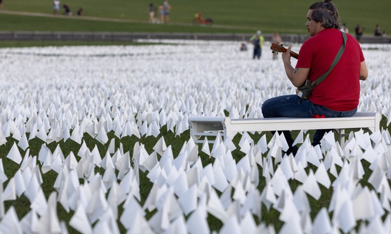 A man sits beside white flags placed on the National Mall to honor the lives lost to COVID-19 in Washington, D.C., the United States, Sept. 18, 2021.(Photo: Xinhua)