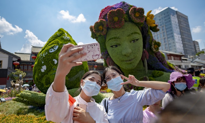 Visitors take selfies in front of a plant sculpture at the Jinbi Square in Kunming, southwest China's Yunnan Province, Oct. 2, 2021. The first part of the 15th meeting of the Conference of the Parties to the UN Convention on Biological Diversity (COP15) is set to kick off in Kunming on Oct. 11.(Photo: Xinhua)