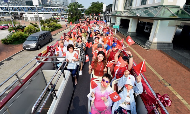 Hong Kong residents wave the Chinese national flags and the regional flags of the Hong Kong Special Administrative Region on a tour bus in south China's Hong Kong, Oct. 1, 2021. (Xinhua/Lo Ping Fai)