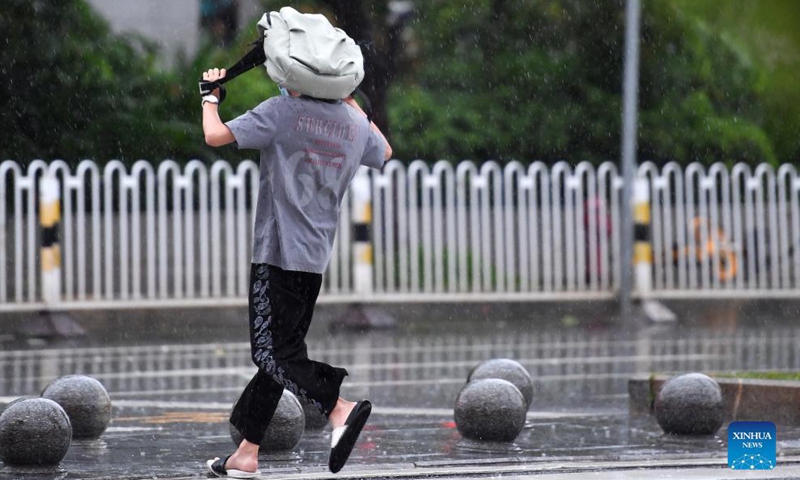A pedestrian runs to take shelter from rain in Haikou, capital of south China's Hainan Province, Oct. 8, 2021. Lionrock, the 17th typhoon to affect China this year, is heading toward the island province of Hainan, according to local meteorological authorities.Photo:Xinhua