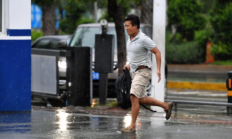 A pedestrian runs to take shelter from rain in Haikou, capital of south China's Hainan Province, Oct. 8, 2021.Photo:Xinhua