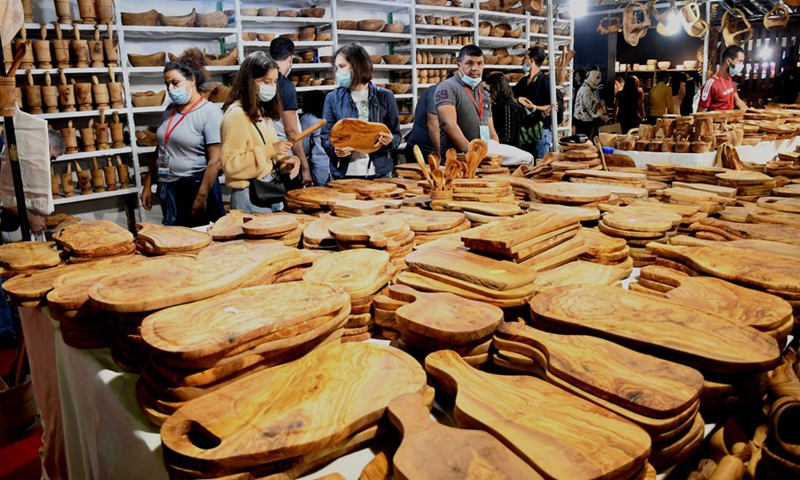 People shop for cutting boards made of olive wood during an innovation salon of handicrafts in Tunis, Tunisia, on Oct. 9, 2021. (Photo: Xinhua)