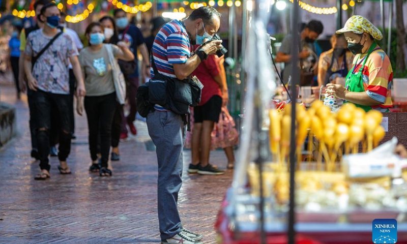 A man takes photos in the Ong Ang walking street in Bangkok, Thailand, on Oct. 15, 2021. Closed due to the COVID-19 pandemic for several months, the Ong Ang walking street reopened on Friday.Photo:Xinhua