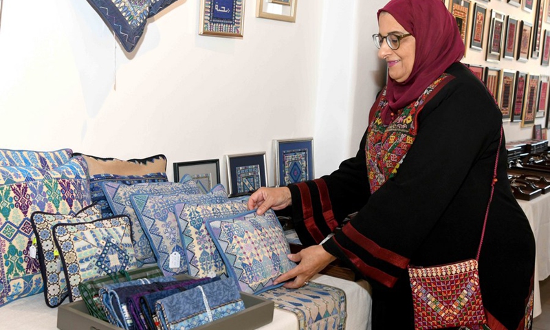 A woman arranges exhibits at an exhibition of the Palestinian heritage in Kuwait City, Kuwait, on Oct. 18, 2021.(Photo: Xinhua)