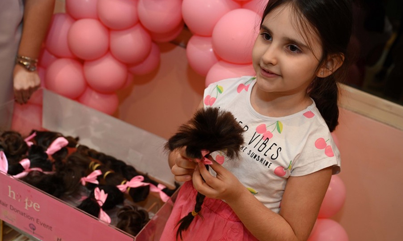 A girl holds her hair during a hair donation event in Hawalli Governorate, Kuwait, on Oct. 19, 2021.(Photo: Xinhua)