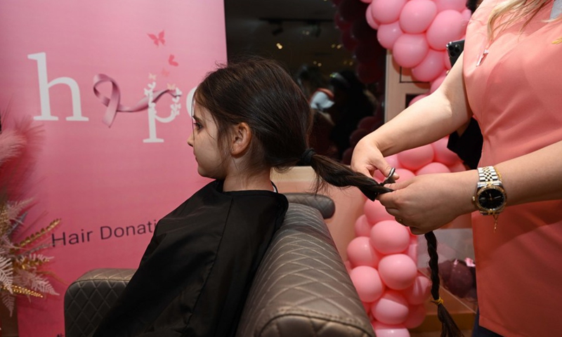 A hairdresser cuts a girl's hair during a hair donation event in Hawalli Governorate, Kuwait, on Oct. 19, 2021.(Photo: Xinhua)