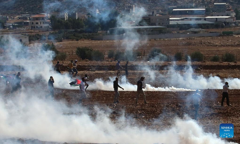 Palestinian protesters run to take cover from tear gas canisters fired by Israeli soldiers during a protest the expansion of Jewish settlements in the West Bank village of Beit Dajan, east of Nablus, on Oct. 22, 2021(Photo: Xinhua)