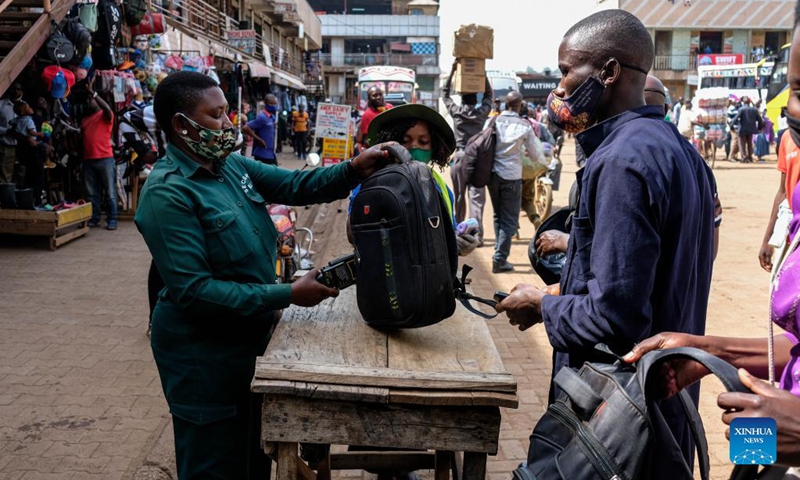 A bus security officer (L) checks luggage of a passenger at a bus terminal in Kampala, Uganda, on Oct. 26, 2021. Police on Tuesday morning spent several hours at the bus terminals in the capital Kampala, urging people to be vigilant and report any suspicious characters. Bus operators were also instructed to resume security checks of all passengers boarding.(Photo: Xinhua)