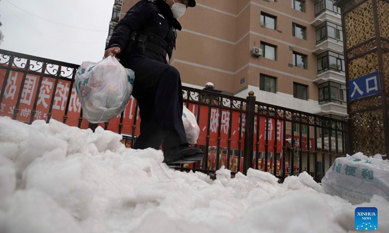 A police officer transports daily life necessities for residents at a community in Pingfang District, Harbin, northeast China's Heilongjiang Province, Nov. 8, 2021. Despite the low temperature in Harbin, those who work outdoors are braving the cold wind, rain and snow to secure the COVID-19 epidemic prevention and control.(Photo: Xinhua)