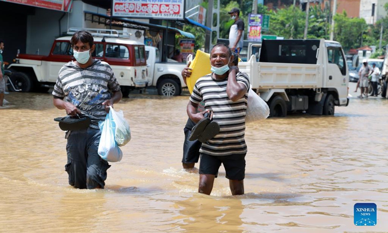 People wade through a flooded road in Kochchikade, a town in Negombo, Sri Lanka, on Nov. 10, 2021. The death toll from heavy rains lashing Sri Lanka rose to 11, while 7,000 people have been affected, the Disaster Management Center said on Tuesday.(Photo: Xinhua)