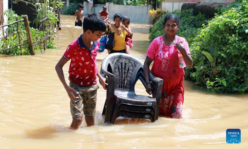 People wade through a flooded road in Kochchikade, a town in Negombo, Sri Lanka, on Nov. 10, 2021. The death toll from heavy rains lashing Sri Lanka rose to 11, while 7,000 people have been affected, the Disaster Management Center said on Tuesday.(Photo: Xinhua)