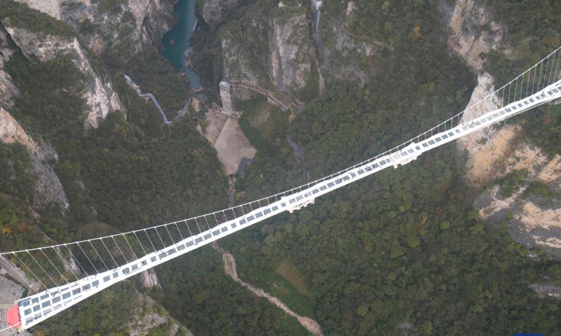 Aerial photo taken on Nov. 12, 2021 shows tourists playing on Zhangjiajie Grand Canyon's glass-bottomed bridge, central China's Hunan Province. The 430-meter long, six-meter wide bridge, linking two steep cliffs 300 meters above the ground, is paved with 99 panes of three-layer transparent glass.Photo:Xinhua