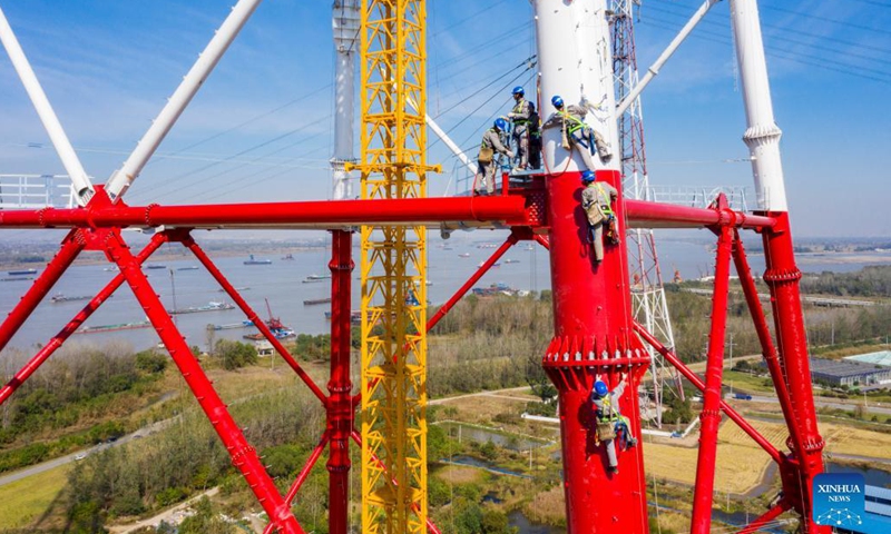 Aerial photo taken on Nov. 11, 2021 shows workers working on a power transmission tower by the Yangtze River in Wuhu, east China's Anhui Province.Photo:Xinhua