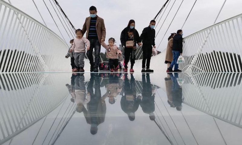Tourists walk on a glass-bottomed bridge at Zhangjiajie Grand Canyon, central China's Hunan Province, Nov. 12, 2021. The 430-meter long, six-meter wide bridge, linking two steep cliffs 300 meters above the ground, is paved with 99 panes of three-layer transparent glass.Photo:Xinhua