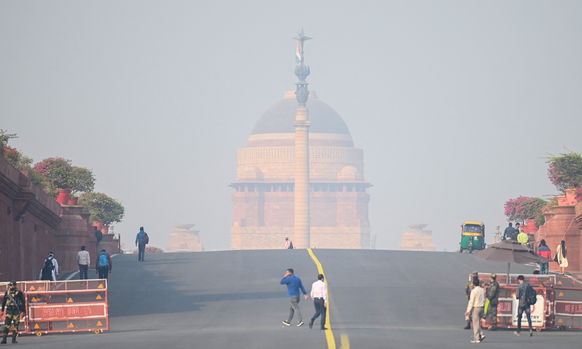 People walk near the presidential palace amid heavy smog conditions in New Delhi, India on Monday. Photo: AFP