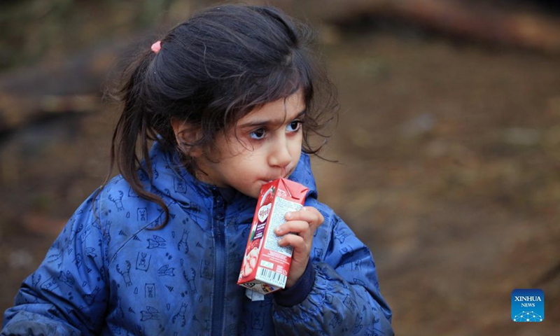 A child drinks a beverage at a refugee camp near the Belarusian-Polish border in Belarus, Nov. 14, 2021. Belarusian President Alexander Lukashenko ordered on Nov. 13 to set up tents and distribute relief supplies to refugees gathered near the Belarusian-Polish border.(Photo: Xinhua)