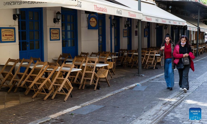 People walk past a closed restaurant in Athens, Greece, on Nov. 16, 2021. Restaurants and cafes across Greece remained closed on Tuesday while a demonstration was held in Athens demanding further state support under the new COVID-19 restrictions introduced by the government this autumn to tackle the latest surge in infection rates.  (Xinhua)