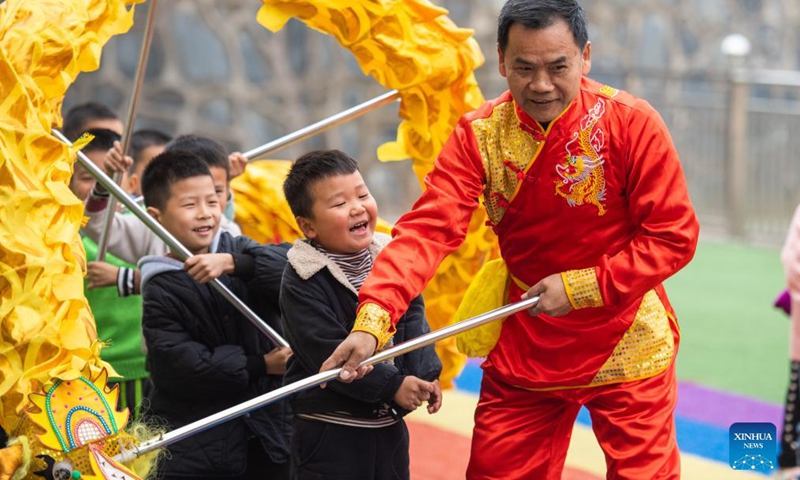 Children learn dragon dance from a folk artist at a kindergarten in Yaotianping Town in Dingcheng District of Changde, central China's Hunan Province, Nov. 17, 2021. The kindergarten invited folk artists to give a dragon dance and lion dance lesson to the children, providing small kids an opportunity to have a close watch on the local intangible cultural heritage. (Xinhua)