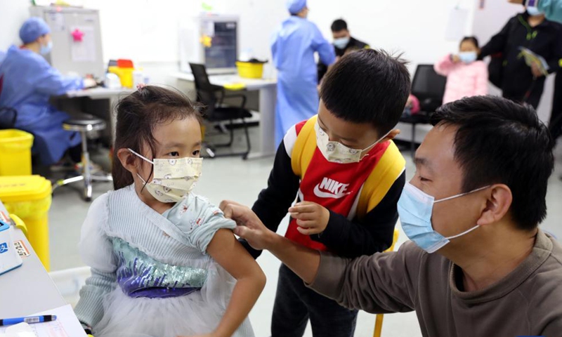 A five-year-old girl, accompanied by her father and brother, gets vaccinated at a vaccination site in Xuhui District of Shanghai, east China, Nov. 20, 2021.Photo:Xinhua