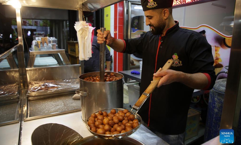 A Palestinian vendor makes Luqmat al Qadi, a traditional pastry made of leavened and deep fried dough, soaked in syrup, in Gaza City, on Nov. 21, 2021. (Photo by Rizek Abdeljawad/Xinhua) 
