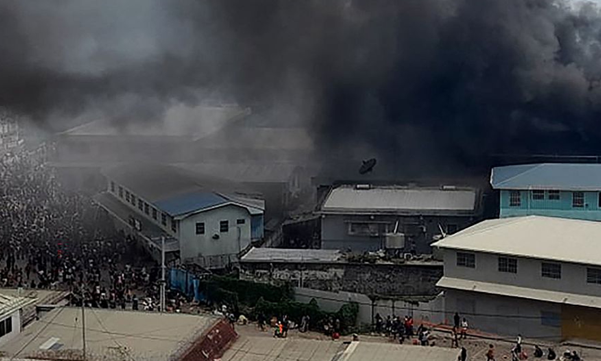 To ulotne zdjęcie zrobione i otrzymane 25 listopada 2021 r. z radia ZFM pokazuje części dzielnicy Chinatown w ogniu w Honiarze na Wyspach Salomona, gdy uczestnicy zamieszek podpalili budynki w stolicy drugiego dnia protestów antyrządowych.  Zdjęcie: VCG