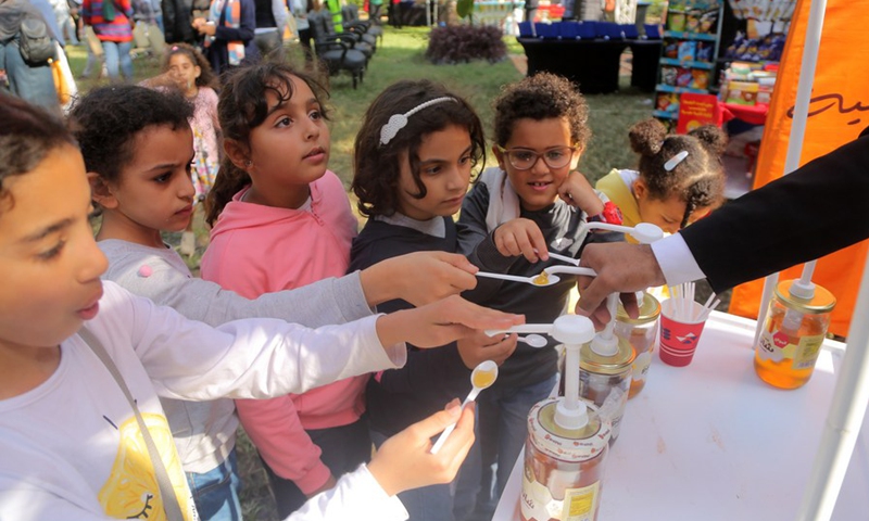 Children taste honey during the 3rd Egyptian Honey Festival in Giza, Egypt, Nov. 24, 2021.(Photo: Xinhua)
