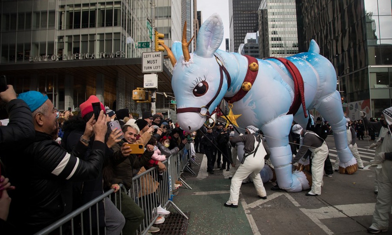 An inflated animal interacts with revelers during the Macy's Thanksgiving Day Parade in New York, the United States, Nov. 25, 2021.(Photo: Xinhua)
