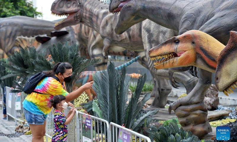 Tourists look at dinosaur models at the Dino Fest in Bangkok, Thailand, on Dec 2, 2021. The Dino Fest kicked off on Dec 2 and will last until Dec 12, showcasing more than 50 dinosaur models.Photo:Xinhua