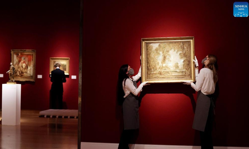 Two staff members hang an artwork for auction on the wall during a media preview of the Christie's London Classic Week auction in London, Britain, Dec. 3, 2021. Christie's London Classic Week presents art from antiquity to the 21st century, spanning five live auctions and four online-only sales.Photo:Xinhua
