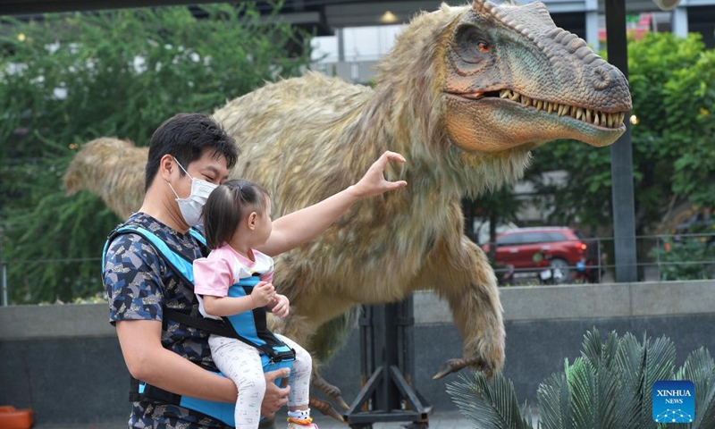 Tourists look at a dinosaur model at the Dino Fest in Bangkok, Thailand, on Dec 2, 2021. The Dino Fest kicked off on Dec. 2 and will last until Dec. 12, showcasing more than 50 dinosaur models.Photo:Xinhua