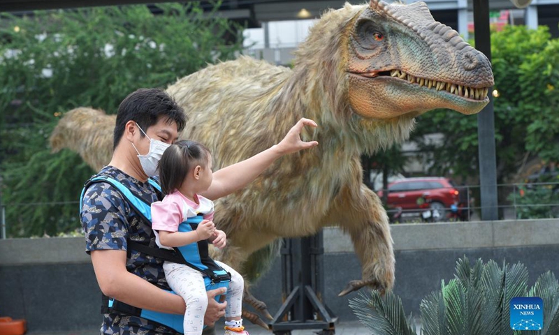 Tourists look at a dinosaur model at the Dino Fest in Bangkok, Thailand, on Dec 2, 2021. The Dino Fest kicked off on Dec. 2 and will last until Dec. 12, showcasing more than 50 dinosaur models.Photo:Xinhua