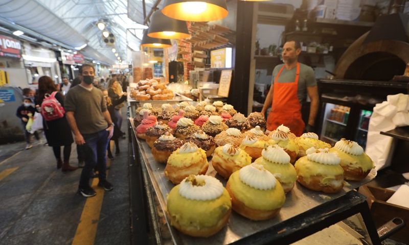 Photo taken on Nov. 24, 2021 shows people selecting Sufganiyot, traditional Hanukkah jelly-filled donuts, during the Jewish holiday of Hanukkah at a patisserie in Jerusalem.(Photo: Xinhua)