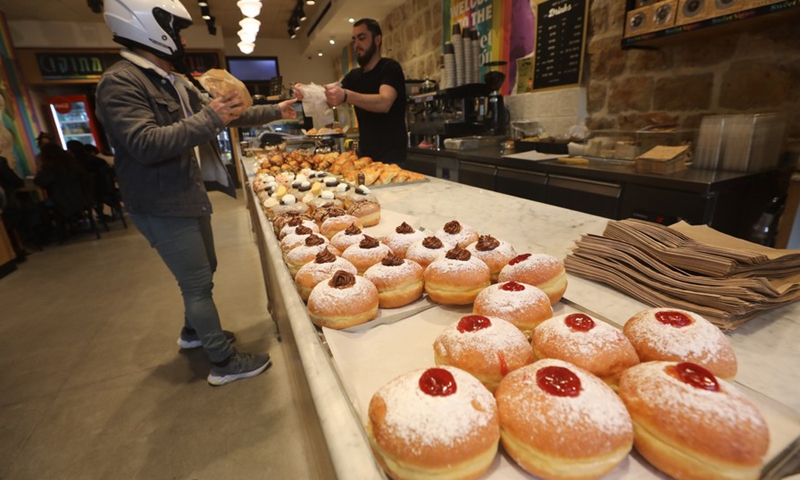 Photo taken on Nov. 24, 2021 shows a customer buying Sufganiyot, traditional Hanukkah jelly-filled donuts, during the Jewish holiday of Hanukkah at a patisserie in Jerusalem.(Photo: Xinhua)