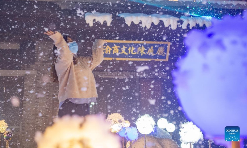 A tourist enjoys a light show and artificial snow in an old street in southwest China's Chongqing Municipality, Dec. 8, 2021.Photo:Xinhua